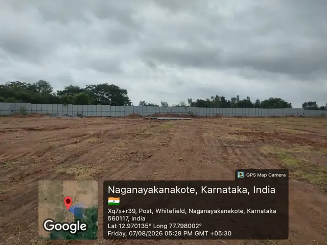 Levelled ground with pipes and soil stockpiled beside the boundary hoarding at the Godrej Florenne site, Soukya Road, 7 August 2026